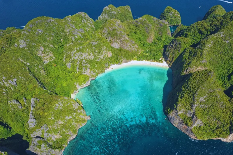 Aerial view of a beautiful Phi Phi Island beach, with lush greenery and crystal-clear water.