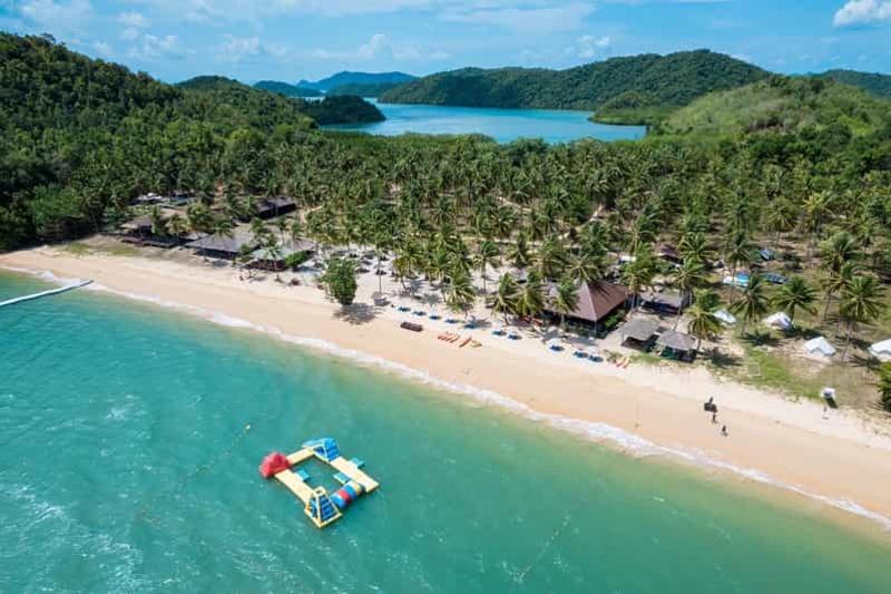 Beach resort in Phuket with inflatable water toys and palm trees along the shore.
