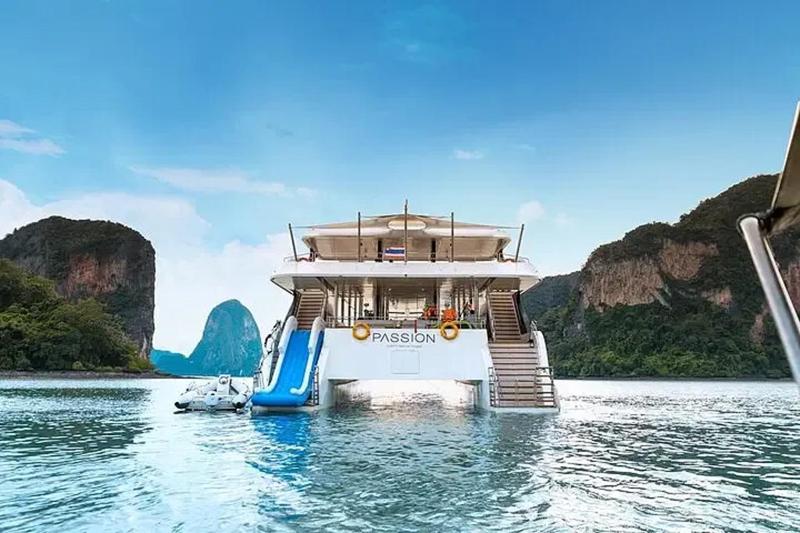 Passion yacht in tropical waters with a slide and scenic mountain views, offering an unforgettable e