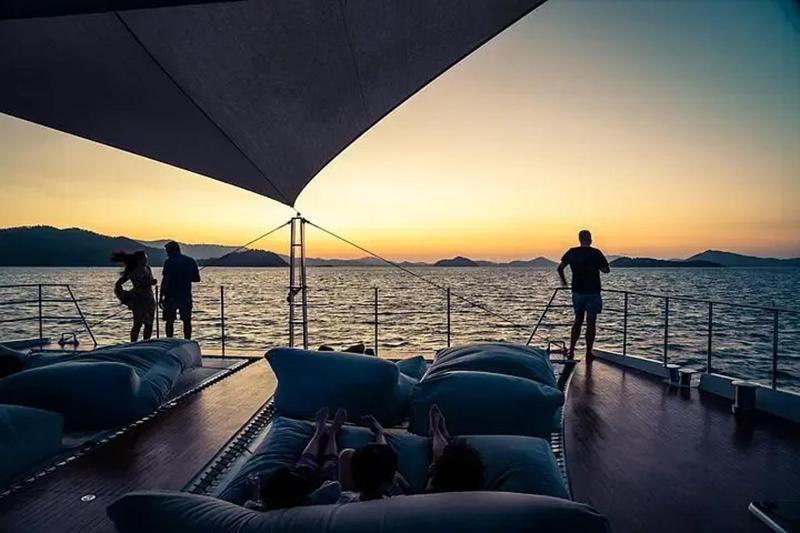 Luxury yacht deck at sunset with comfortable lounge seating, perfect for relaxing by the sea.