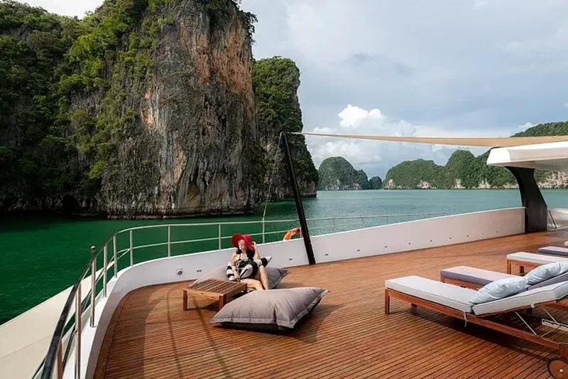 Luxury yacht lounge with large windows, offering stunning views of ocean cliffs and crystal-clear wa
