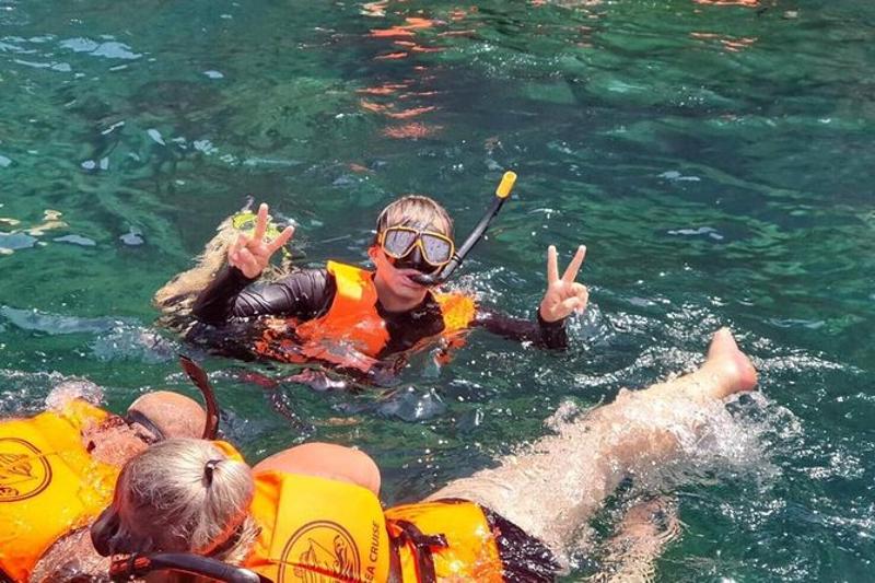 A snorkeler posing in clear tropical waters, surrounded by vibrant coral reefs at a scenic island in