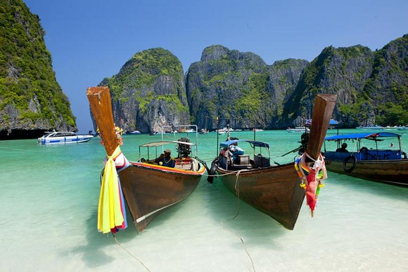 A stunning view of traditional longtail boats on Phi Phi Islands with towering limestone cliffs and 