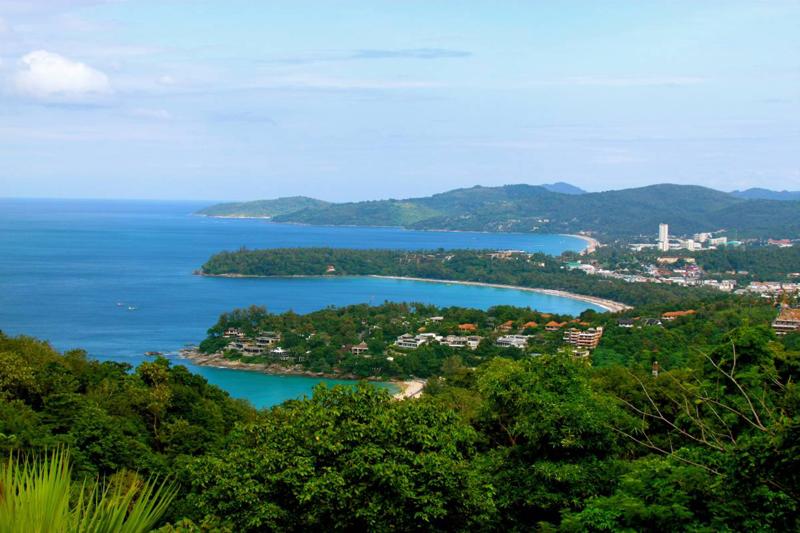 A panoramic view of Karon Beach from the Karon Viewpoint, Phuket, with clear blue waters and the vib
