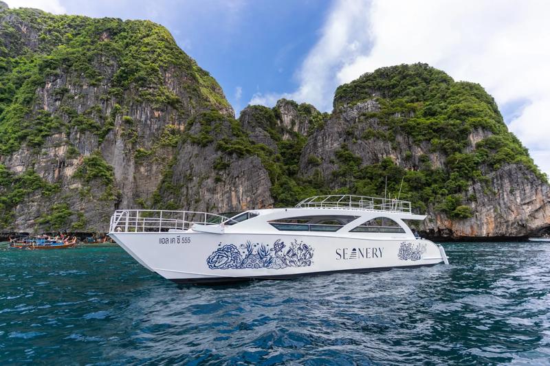 A luxury boat sailing on turquoise water, surrounded by rocky hills in the background.
