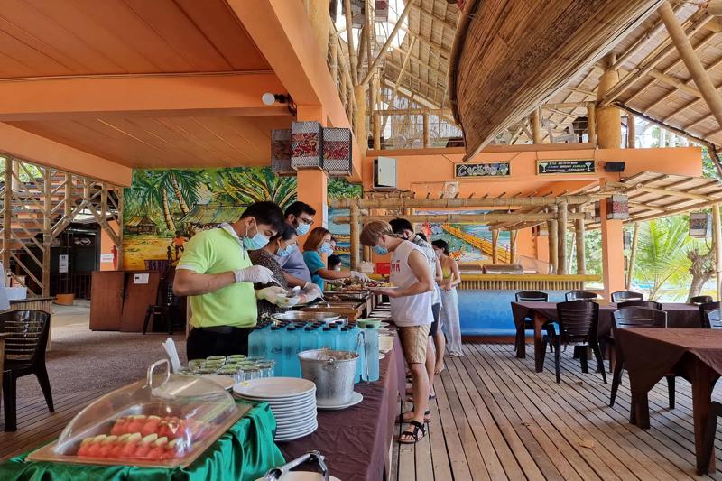An outdoor restaurant in Thailand with a buffet setup and guests enjoying a variety of food.