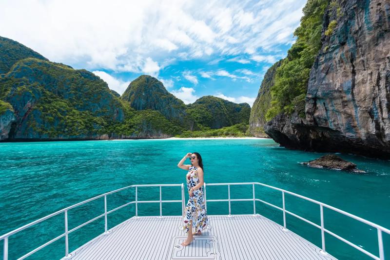 A woman enjoying a scenic view from a boat, surrounded by lush green mountains and tropical waters.