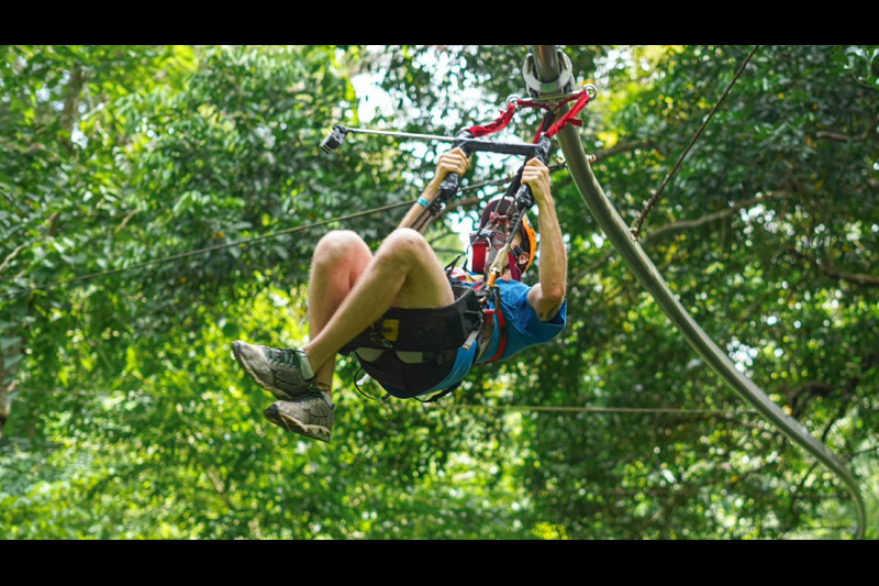 Tourists walking on a suspension bridge at Hanuman World Phuket, surrounded by lush green jungle.