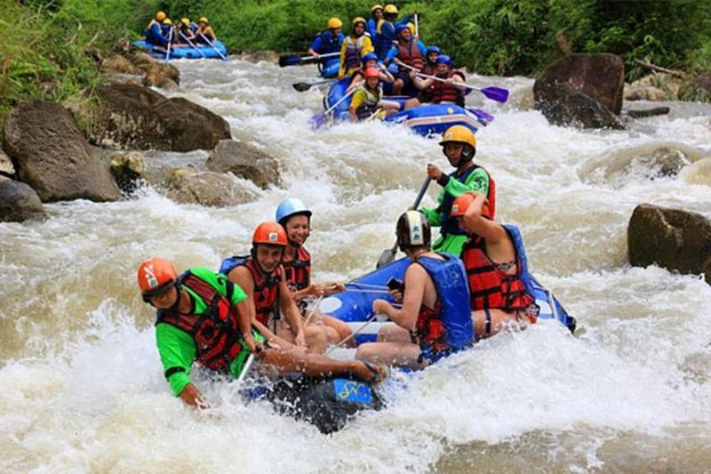 Explore a stunning waterfall while rafting, surrounded by lush tropical greenery.